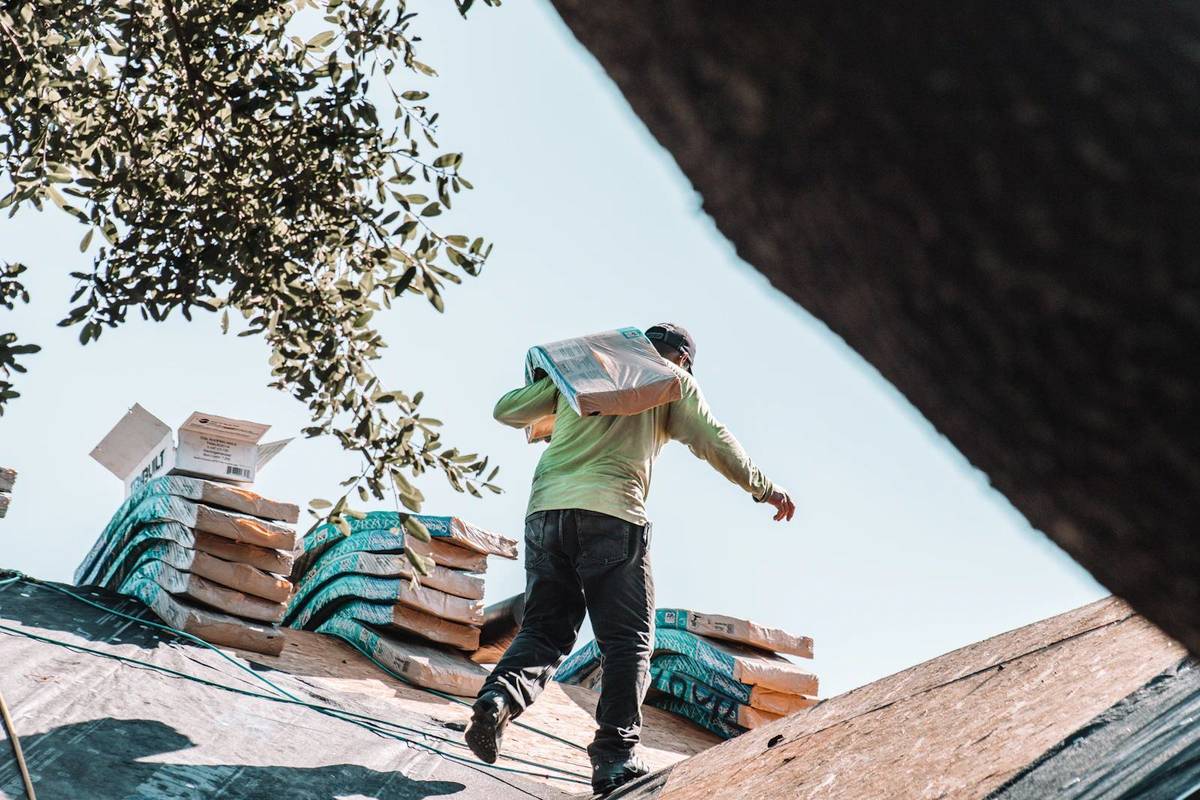 Roofer carrying materials across a roof